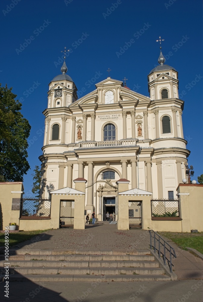 Fototapeta premium Vilnius, Lithuania - Sep 21, 2024: St. Church of Apostles Peter and Paul. People walking in Vilnius. Streets, buildings. Lifestyle in the urban area. Sunny summer day. Selective focus