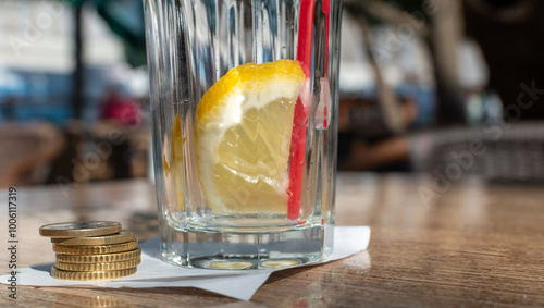 Stack of euro coins on paper bill close-up on table with empty cocktail glass on blurred background