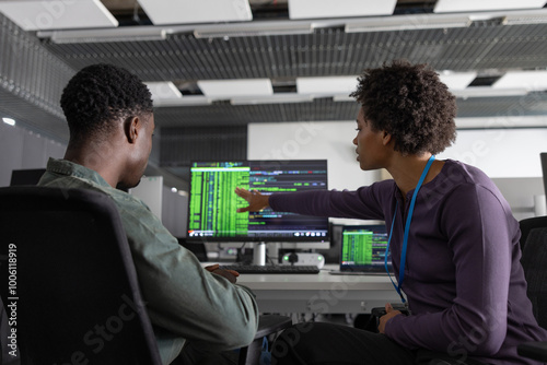 Coworkers discussing computer program in office