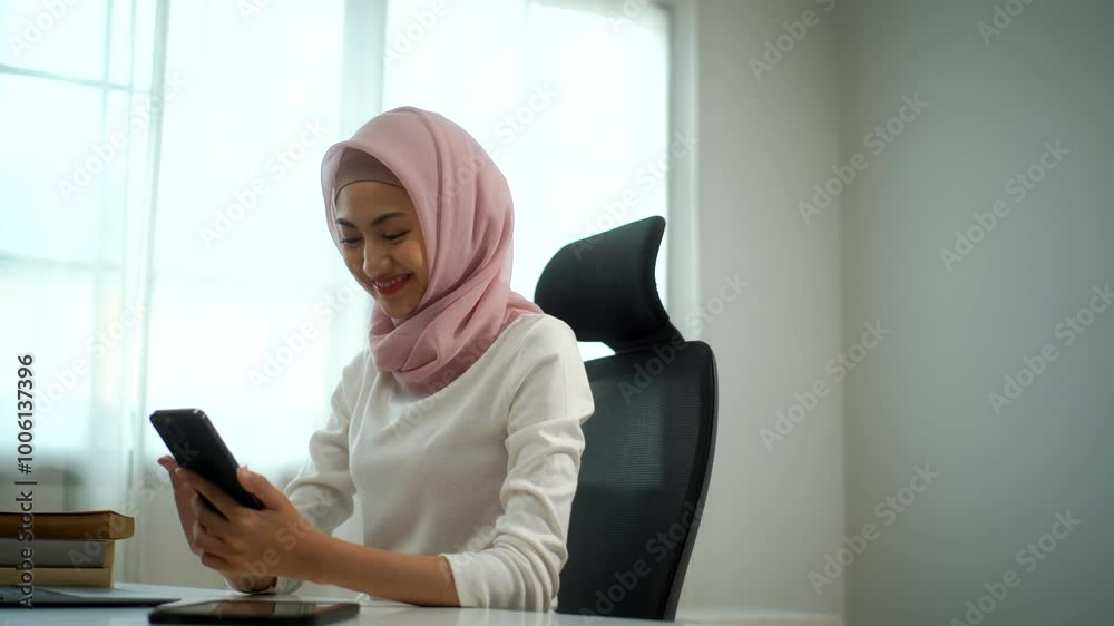 Young cheerful muslim woman in hijab relaxing by checking social media on smartphone while sitting at home office, happy female entrepreneur smiling when shopping online or watching video on mobile.
Young cheerful muslim woman in hijab relaxing by checking social media on smartphone while sitting at home office, happy female entrepreneur smiling when shopping online or watching video on mobile.