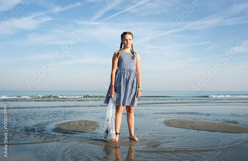 Girl cleaning up plastic waste at the sea.
