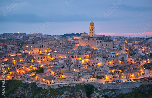 Evening view of the historic city of Matera, Italy, with illuminated buildings and landmark bell tower. photo