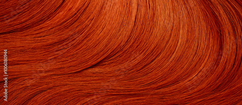 Red hair close-up as a background. Women's long orange hair. Beautifully styled wavy shiny curls. Hair coloring bright shades. Hairdressing procedures, extension.