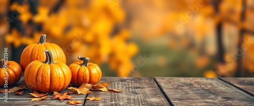 A cozy, horizontal banner showing a collection of bright orange pumpkins and scattered autumn leaves on a rustic wooden table.