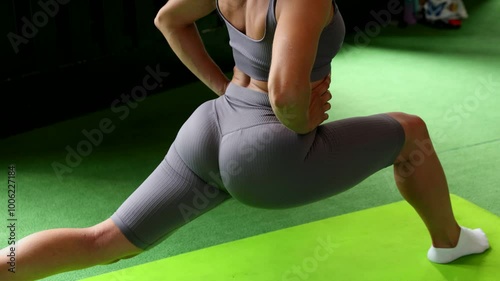 Girl in gray suit in gym training on green background