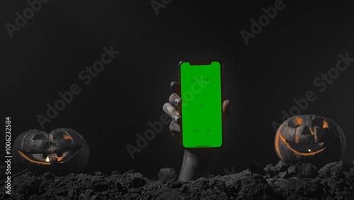 Scary halloween zombie hand raising up from grave ground holds smartphone chroma key green screen, monochrome cinematic retro effect. Mystery halloween concept. photo