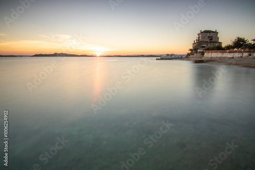 View over the sea into the sunset landscape shot with the historical landmark Byzantine Tower of Prosphorion at the 
Coast of Ouranoupoli, Thessaloniki, Central Macedonia, Greece photo