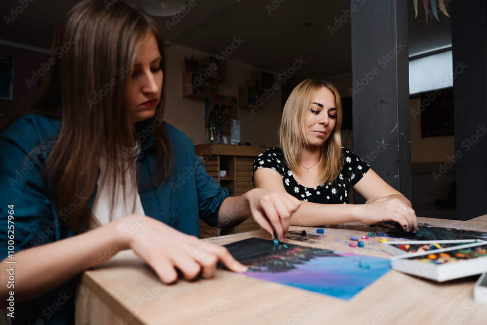 Two women engaged in a creative art session at a cozy indoor studio Two women engaged in a creative art session at a cozy indoor studio
