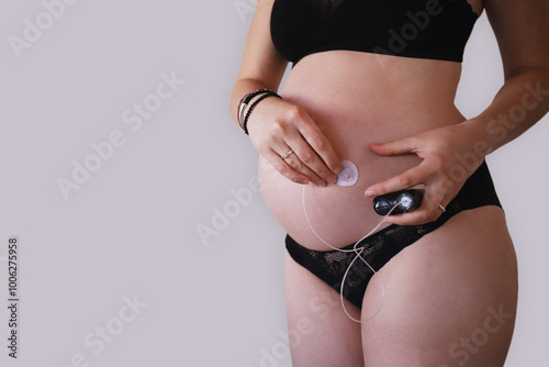 Pregnant woman removing infusion set from belly while holding insulin pump