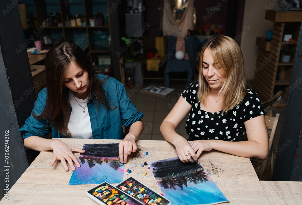 Fototapeta premium Two women creating colorful landscape art together in a cozy indoor space