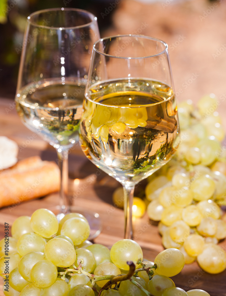Glass of White wine grapes and bread on table in field Glass of White wine grapes and bread on table in field