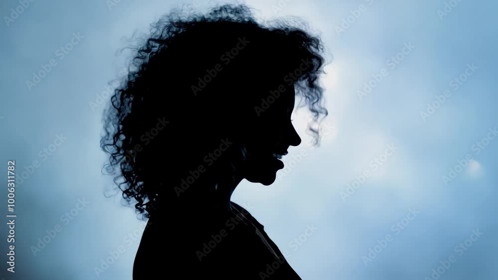 Silhouette of woman with curly hair against blue sky background Silhouette of woman with curly hair against blue sky background