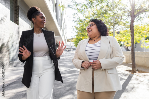 Two professional women laughing and walking outdoors photo