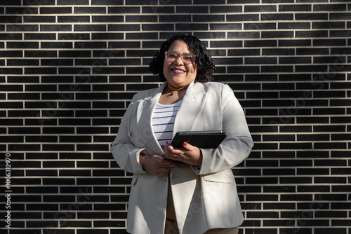 Professional woman holding tablet in front of a brick wall photo