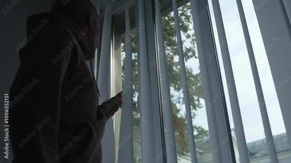 The man approaches the open window and closes it. Silhouette of a man who closes the window after airing the room. The guy turns the handle on the window frame. The man approaches the open window and closes it. Silhouette of a man who closes the window after airing the room. The guy turns the handle on the window frame.