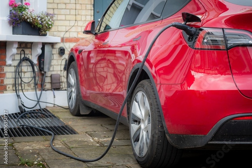 Electric car being charged outside at home in typical British suburban residential setting