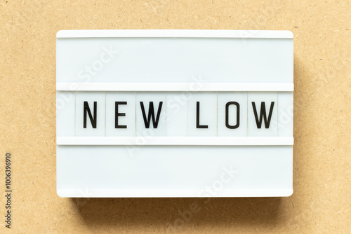 Lightbox with word new low on wood background photo