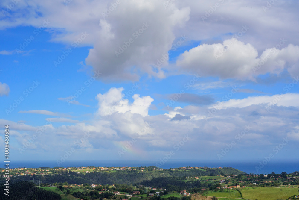Rayo de arco iris en cielo nublado sobre litoral rural de Asturias Rayo de arco iris en cielo nublado sobre litoral rural de Asturias