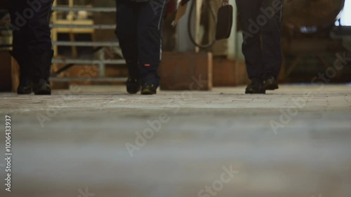 Close-up of workers' feet walking on the tiled floor of a factory.
