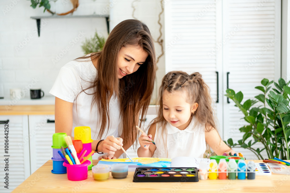 mom and a drawing teacher teaches a little girl child to draw with paints and colored pencils, fun drawing lessons at an art school mom and a drawing teacher teaches a little girl child to draw with paints and colored pencils, fun drawing lessons at an art school