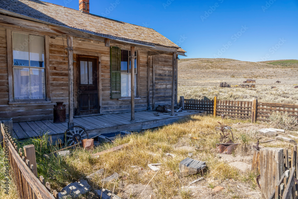 A weathered wooden house with porch in Bodie ghost town, California. The abandoned frontier homestead showcases preserved Wild West architecture against a barren desert landscape. A weathered wooden house with porch in Bodie ghost town, California. The abandoned frontier homestead showcases preserved Wild West architecture against a barren desert landscape.