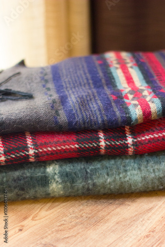 Stack of folded knitted wool scarf, Season of warm knitwear red, green, wood.