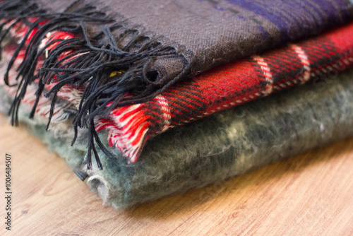 Stack of folded knitted wool scarf, Season of warm knitwear red, green, wood.