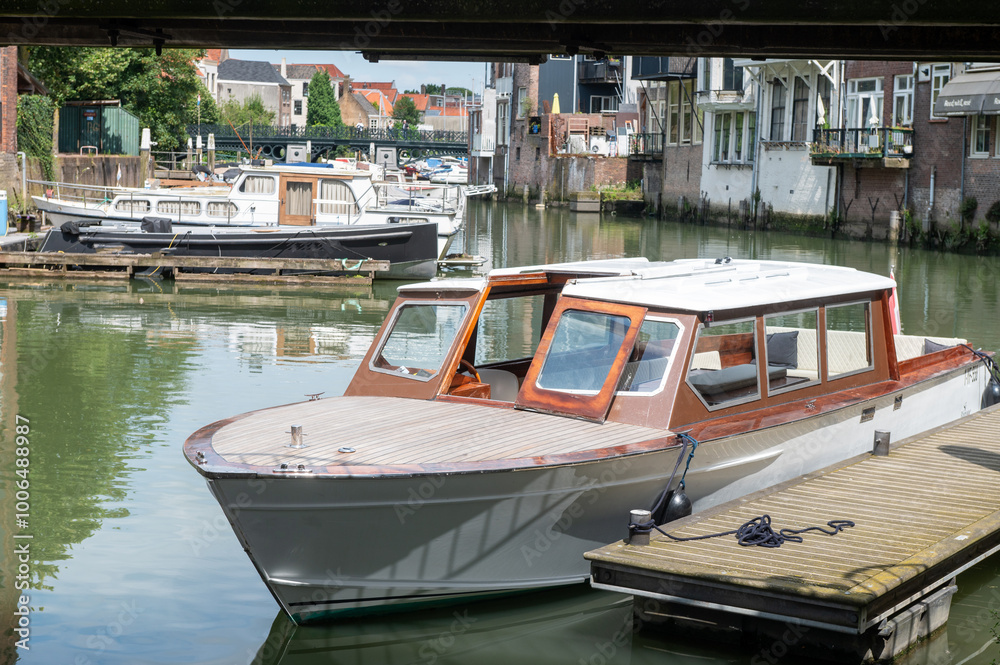 Obraz premium Small wooden boat docked in a peaceful canal surrounded by historic buildings.