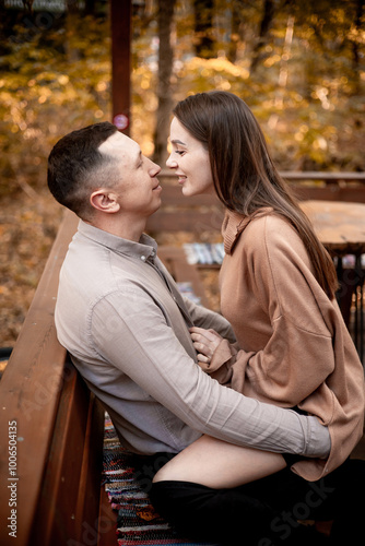 a young couple guy with a girl in autumn in a cafe in brown and orange tones on an outdoor terrace hugging and kissing, love or Valentine's day