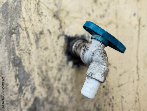 Blue water tap on rough gray cement concrete wall. Concept of saving water, saving energy, no water, drought, summer, dry season. photo