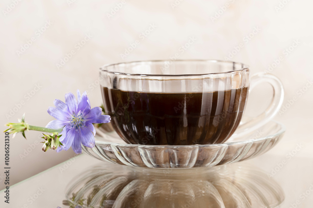 One glass of chicory beverage and flower on glass table with reflection. Close up. Horizontal format One glass of chicory beverage and flower on glass table with reflection. Close up. Horizontal format