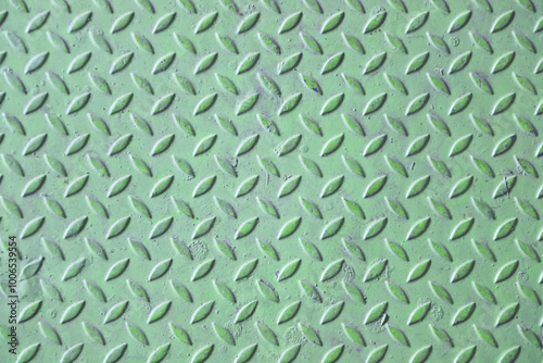 Close-up of green diamond plate metal texture with worn surface.