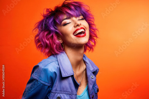 Vibrant young woman with purple hair laughing joyfully, wearing blue leather jacket against orange background, expressing happiness and confidence