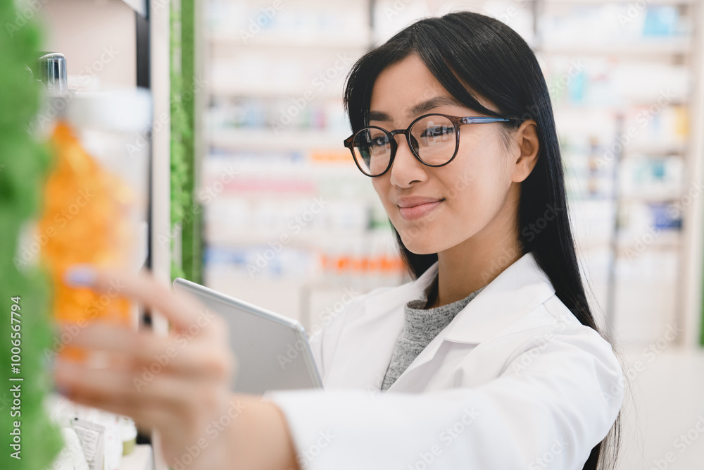 Closeup female asian pharmacist druggist in medical white coat looking for drugs at prescription stretching to pills, vitamins, painkillers, medicines at pharmacy shelves in drugstore Closeup female asian pharmacist druggist in medical white coat looking for drugs at prescription stretching to pills, vitamins, painkillers, medicines at pharmacy shelves in drugstore