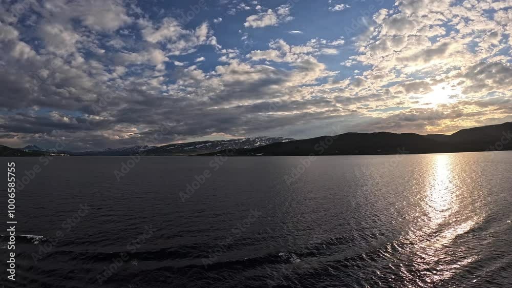 Tromsøya, Romssasuolu, Tromsø Municipality, Troms, Norway - timelapse arriving with cruise ship during sunset on cloudy afternoon with jetskies accompany to port in Tromsøysundet strait