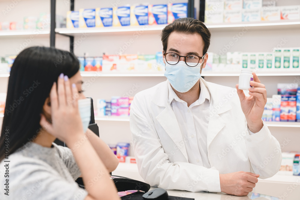 Obraz premium Male pharmacist druggist in face mask against coronavirus advising remedy, painkillers, drugs, medicines, pills for female customer client buyer suffering from headache migraine in pharmacy drugstore