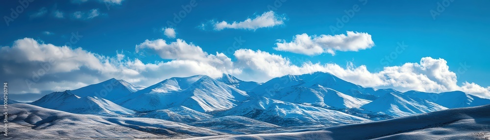 Snow-capped mountains with a clear blue sky and puffy clouds Snow-capped mountains with a clear blue sky and puffy clouds