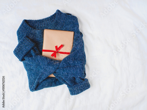 Navy blue sweater with eco wrapped present isolated on white linen background. Flat lay. Top view. Copy space