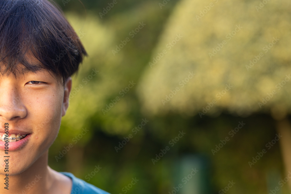 Smiling teenage asian boy with braces outdoors, enjoying nature in garden, copy space Smiling teenage asian boy with braces outdoors, enjoying nature in garden, copy space
