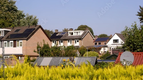 Typical 1970's Dutch brick houses with solar panels and lush greenery in Oosterbeek village. Captured on a sunny day in Oosterbeek, Gelderland, Netherlands photo