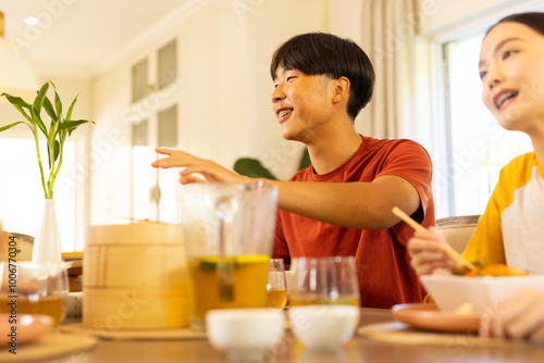 At home, Enjoying meal together, multiracial family sitting at dining table and smiling happily