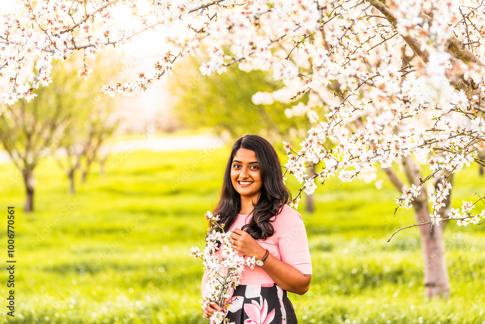 Smiling woman holding almond blossoms in blooming orchard. Smiling woman holding almond blossoms in blooming orchard.