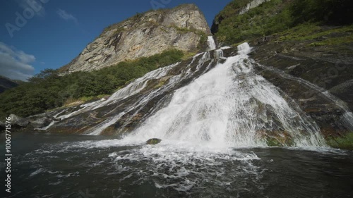 Water pours down the steep cliffs, flowing into the fjord's clear blue waters in this close-up of a Geiranger waterfall. photo