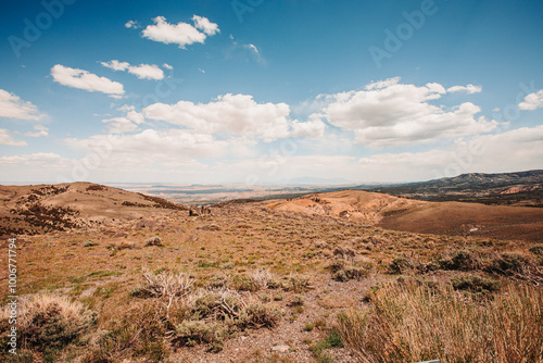 Expansive desert landscape with hills under a bright, partly clo photo