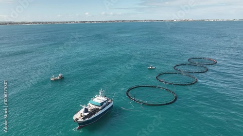 A Mid sized marine vessel tows four fish farms along the west Australian coast. photo