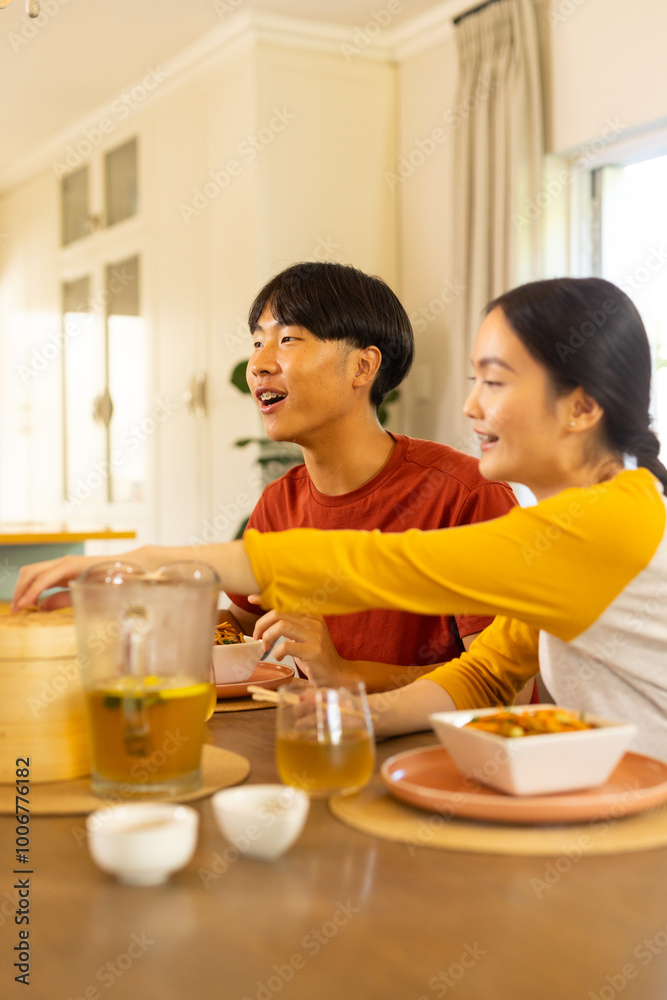 Eating together, young asian brother and sister enjoying meal and conversation at home dining table Eating together, young asian brother and sister enjoying meal and conversation at home dining table