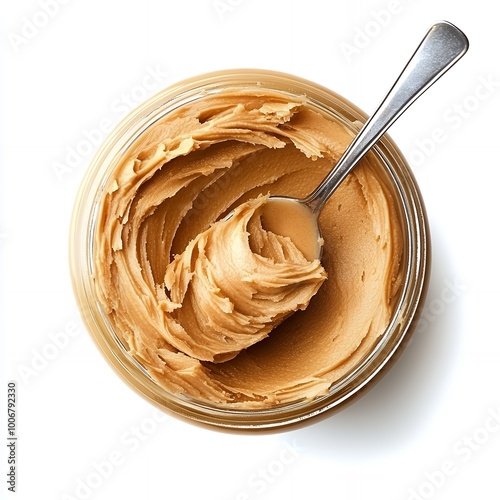 A spoonful of peanut butter in a glass jar.