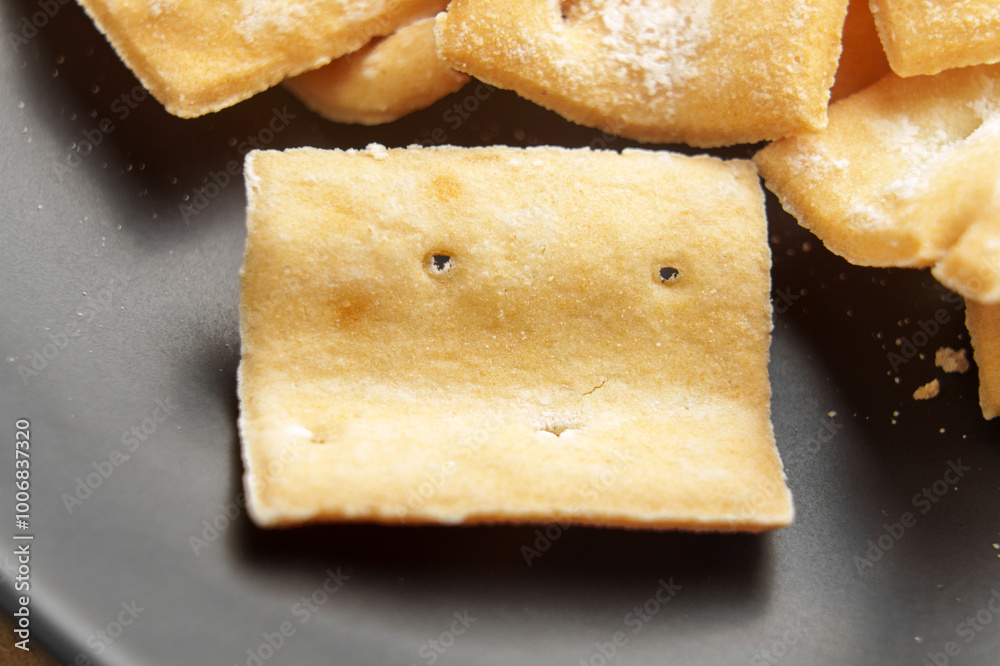 Crispy baked golden crackers with curved form on black plate. Macro shot Crispy baked golden crackers with curved form on black plate. Macro shot