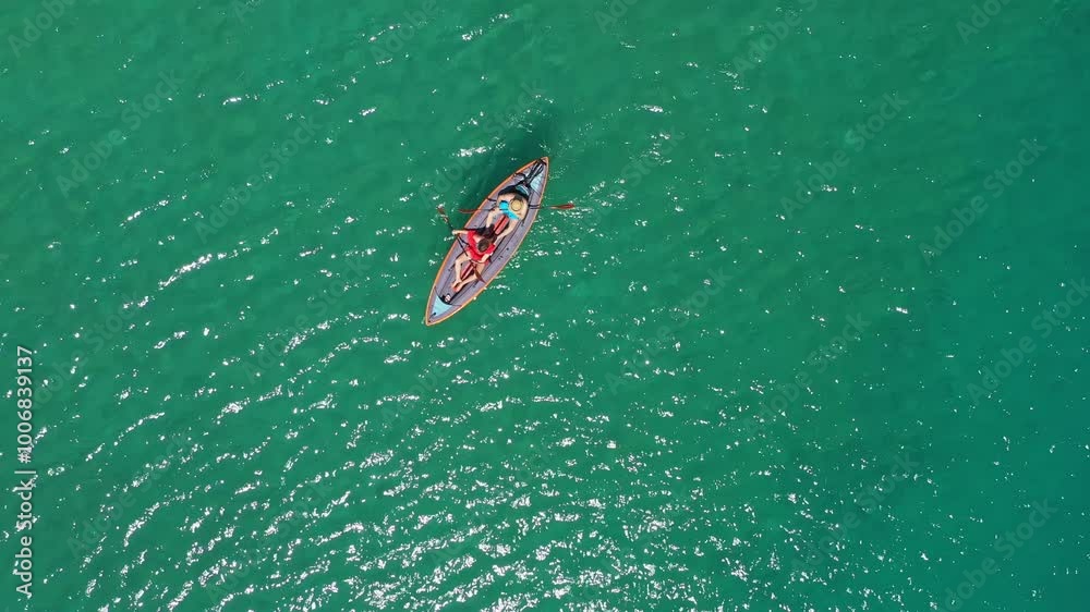 Two tourists paddling a kayak across clear turquoise waters create a vibrant scene of summer adventure and relaxation Two tourists paddling a kayak across clear turquoise waters create a vibrant scene of summer adventure and relaxation
