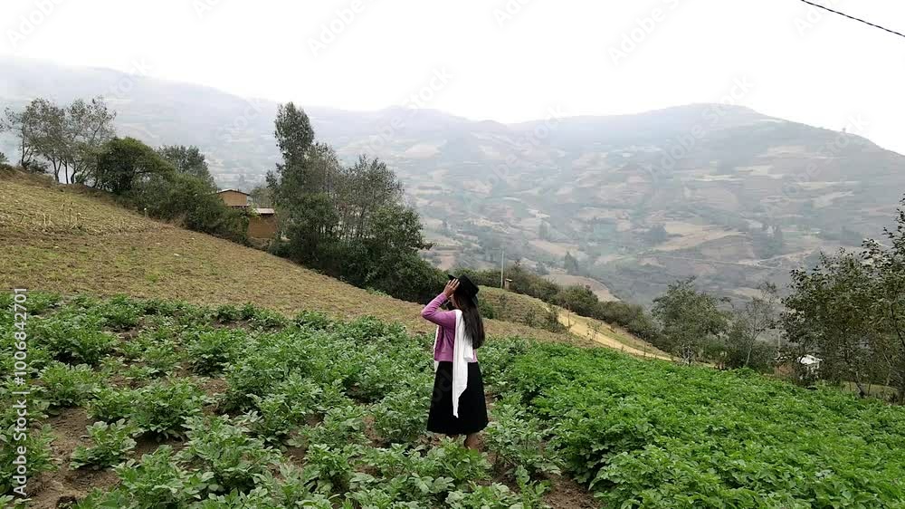 Video de una feliz y bonita campesina con un sombrero hablando por un teléfono celular en los Andes peruanos. Mujer usando teléfono móvil